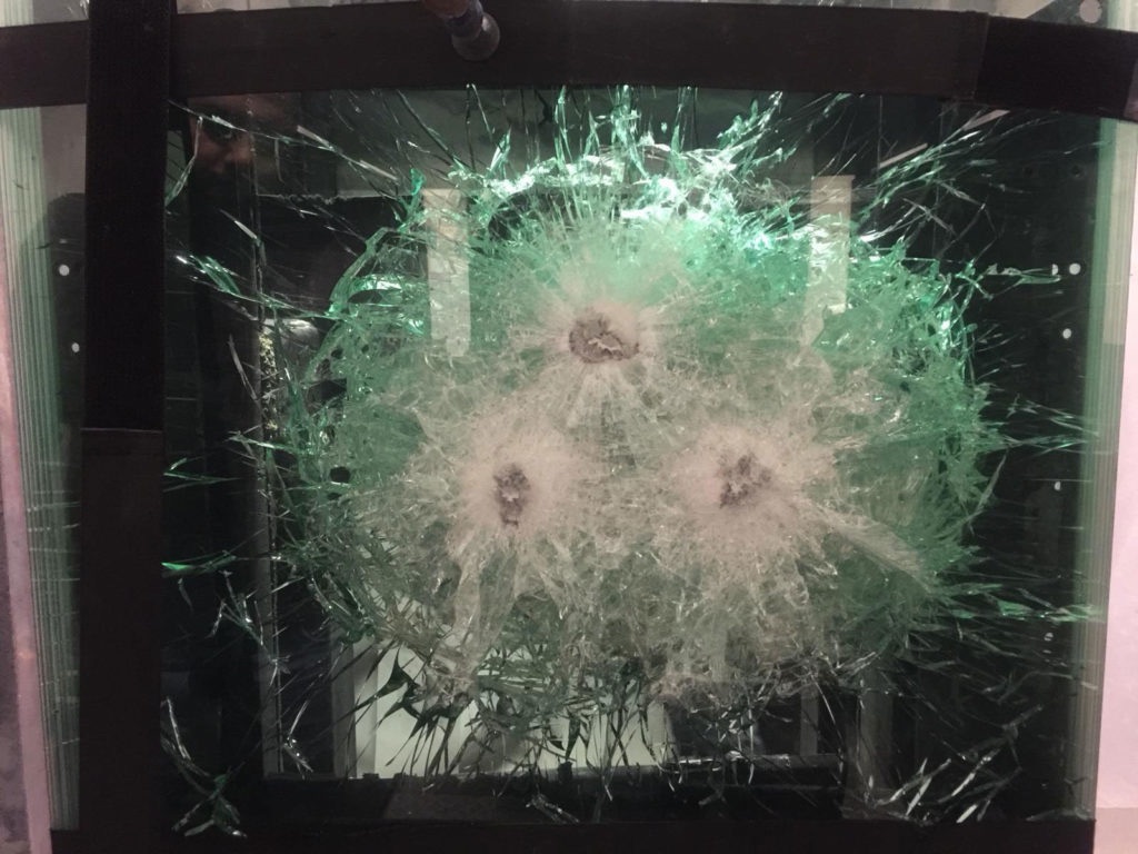 Ballistic glass test panel showing three impact points with no penetration